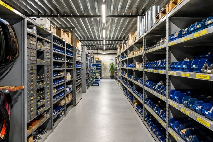 Gang in einem technischen Lager mit gekennzeichneten Regalen und sortierten Ersatzteilen